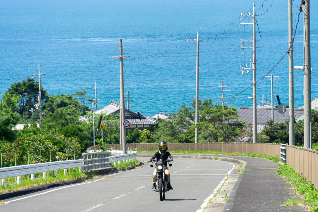 海をバックに走るトリッカーに乗ったカゲ美