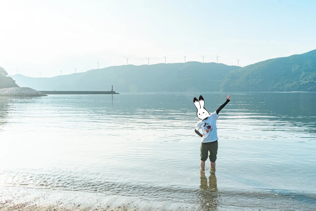ムーンビーチ井野浦で水遊びを楽しむカゲ美。対岸には風車が等間隔に並んでいる。